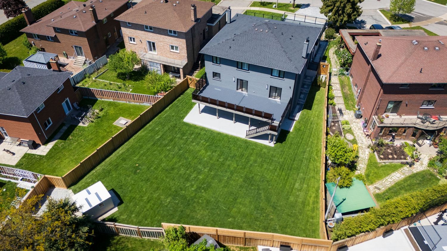Aerial drone view of suburban homes with well-maintained lawns and driveways in a residential neighborhood.