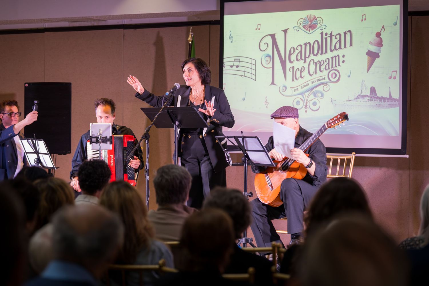 Female vocalist performs Neapolitan Ice Cream show with accordion and guitar musicians on stage.