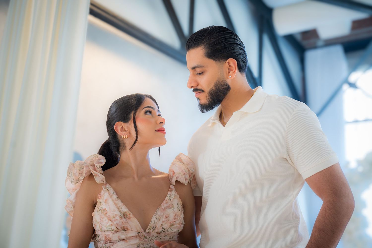 Couple gazes lovingly at each other in a beautifully decorated white floral proposal setting.