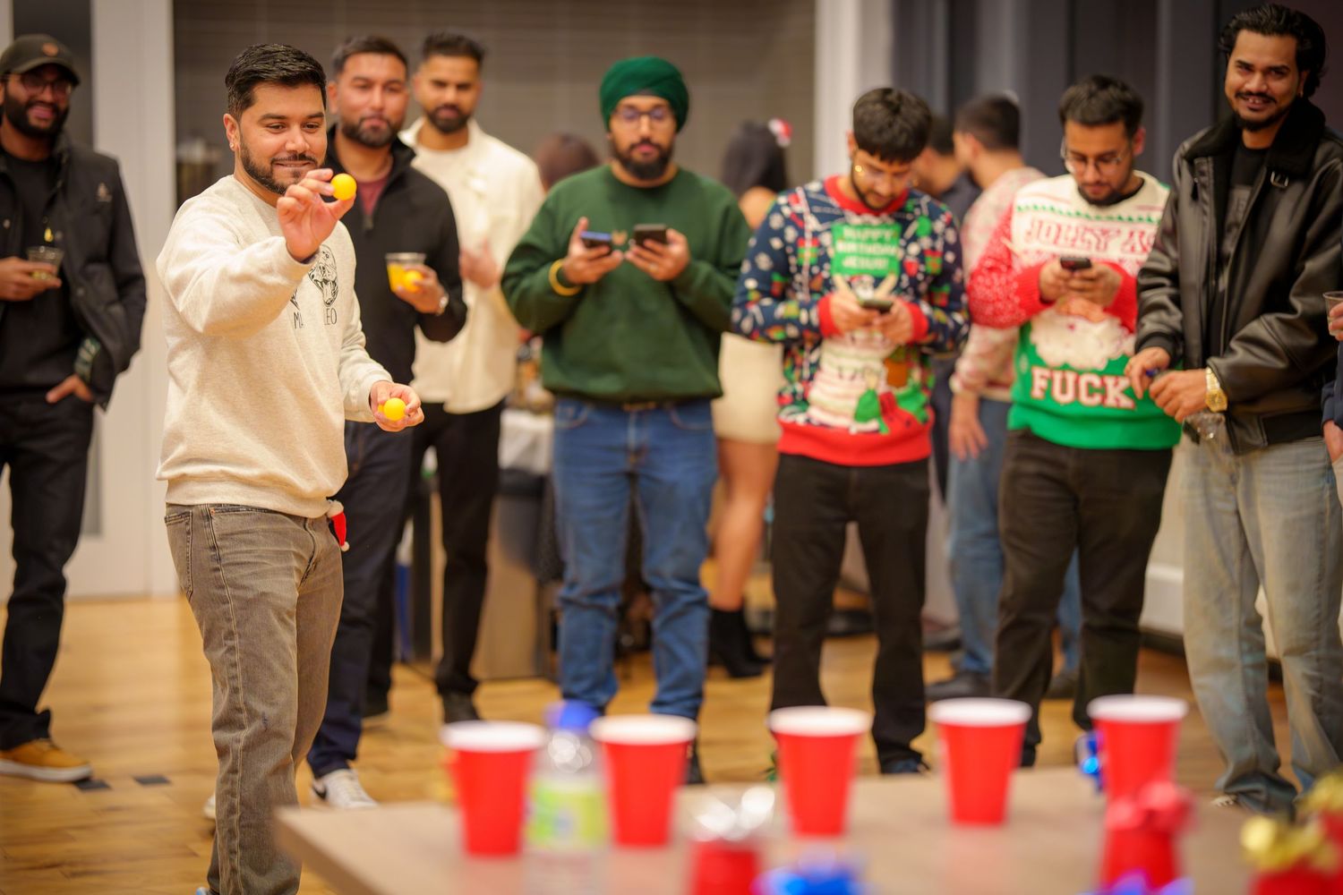Party guests mingling and socializing at an indoor gathering with festive red cups.