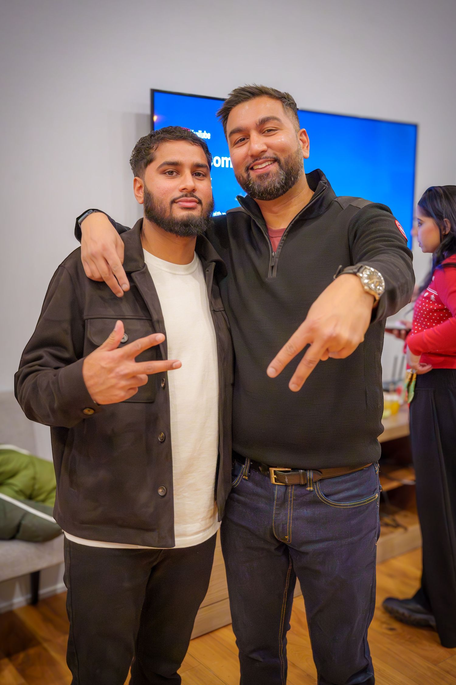 Friends posing together at an indoor social gathering with a blue backdrop.