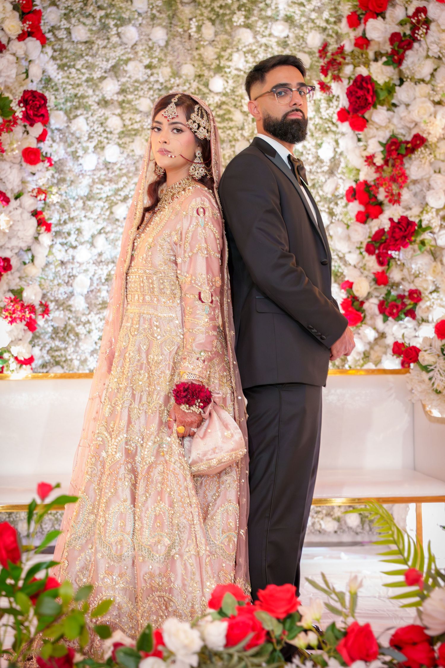 Elegant wedding portraits with red rose decor and shimmering backdrop.