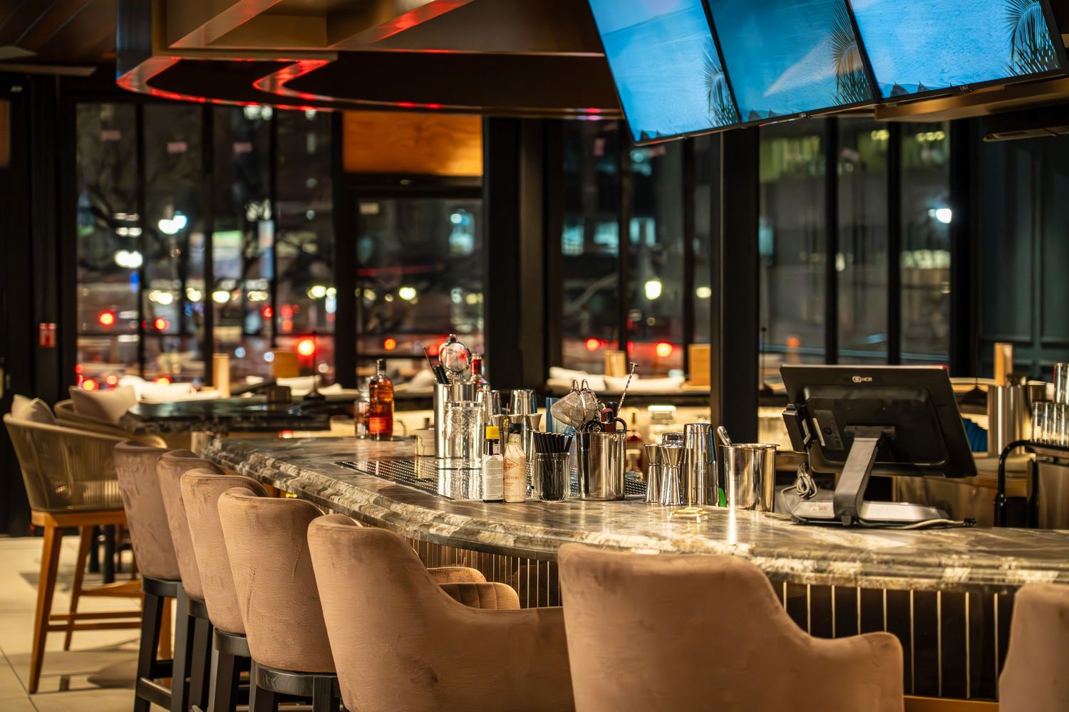 Modern restaurant interior with warm lighting, sleek furniture, and panoramic windows creating an elegant dining atmosphere.