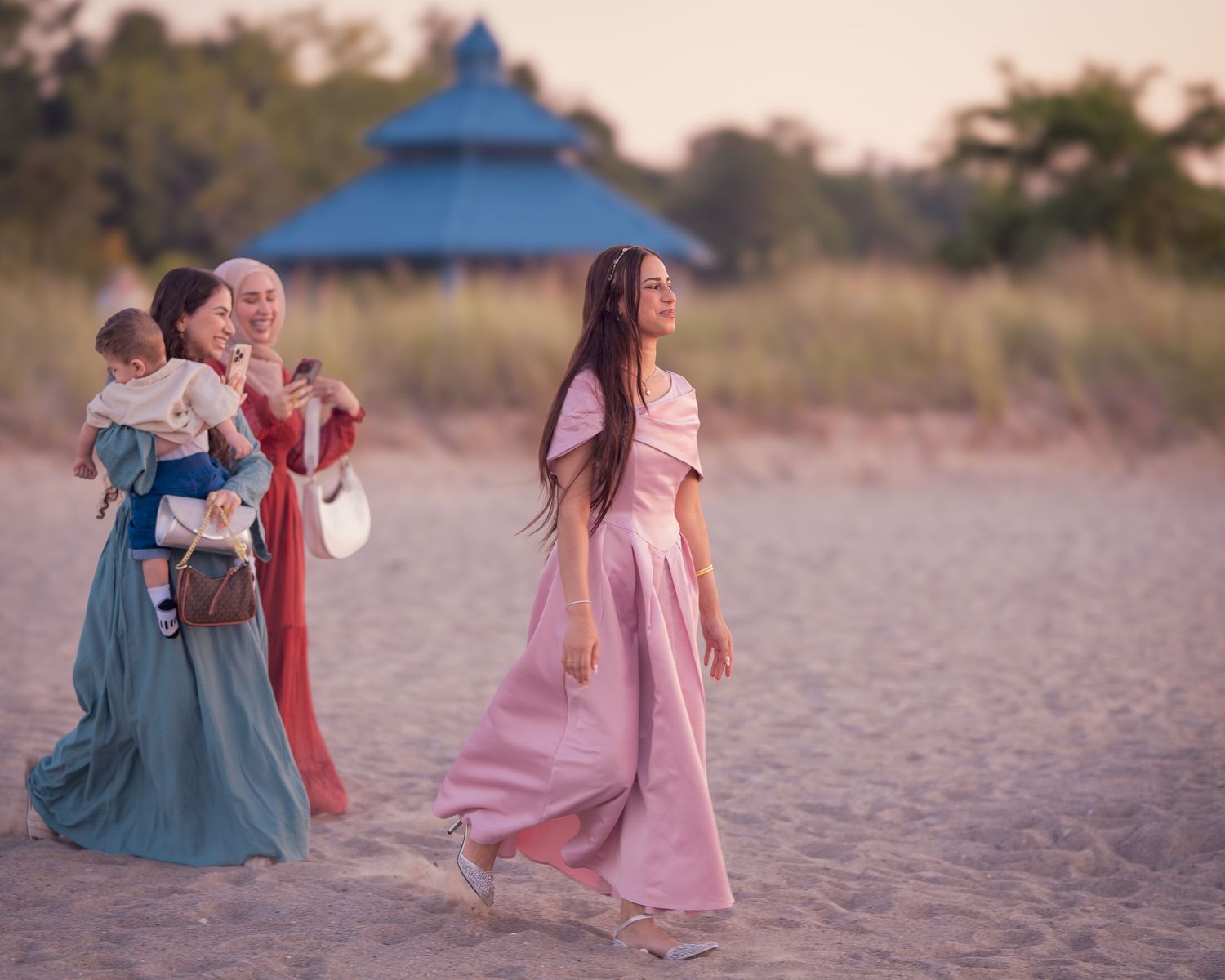 A series of photos showing people in pink and blue clothing sitting and walking along a sandy beach at sunset.
