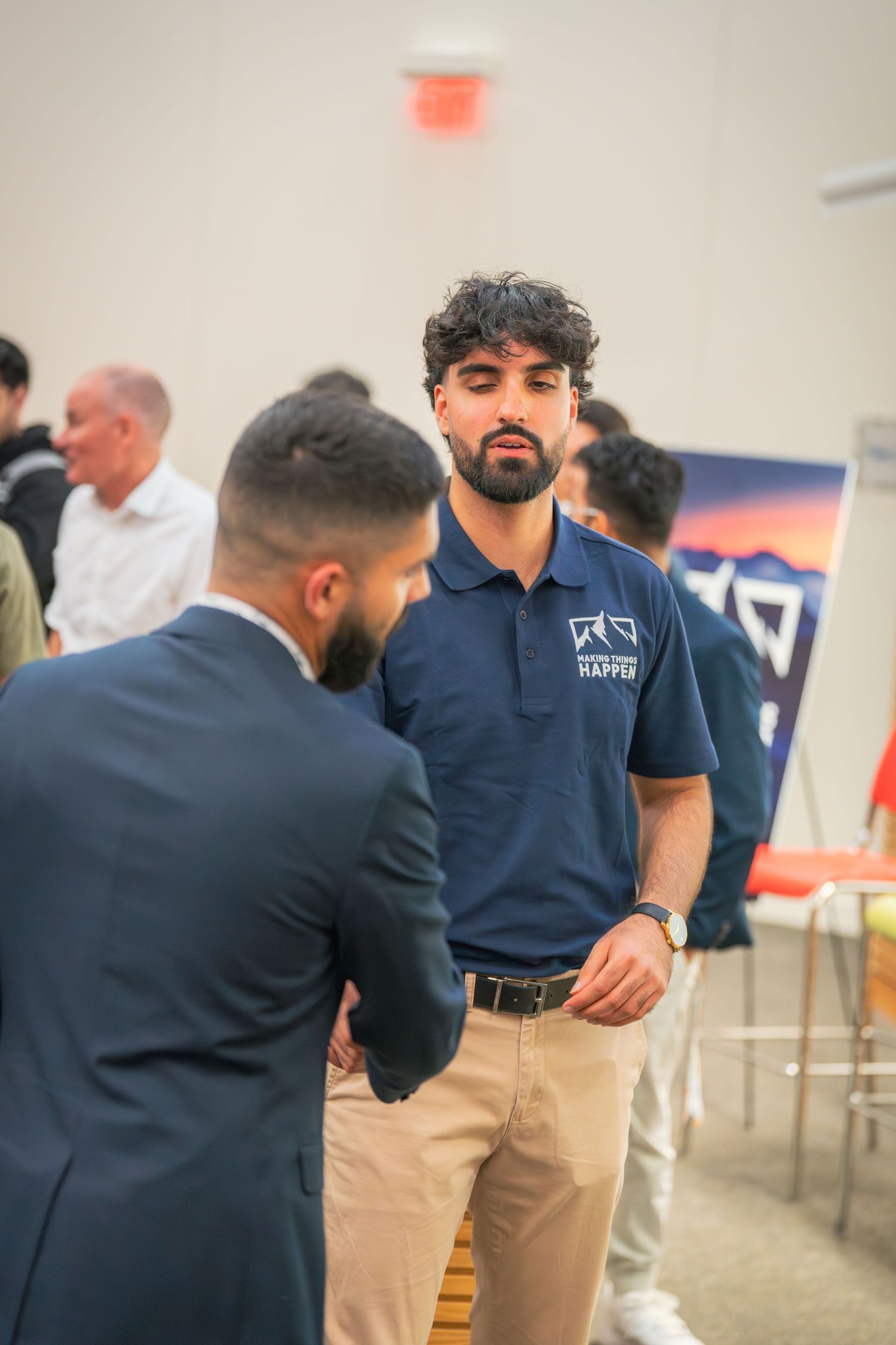 Professional interaction between attendees at business event with branded signage.