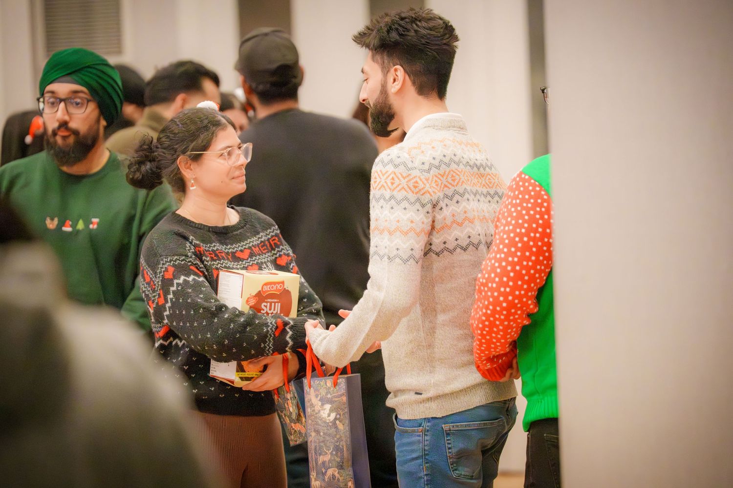 Group enjoying a festive gathering with holiday sweaters and casual attire.