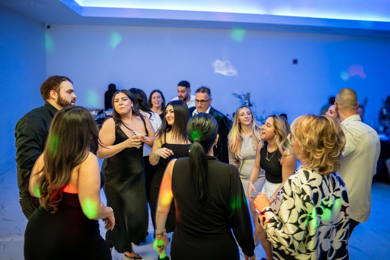 Party crowd dancing and mingling under modern blue LED lighting.