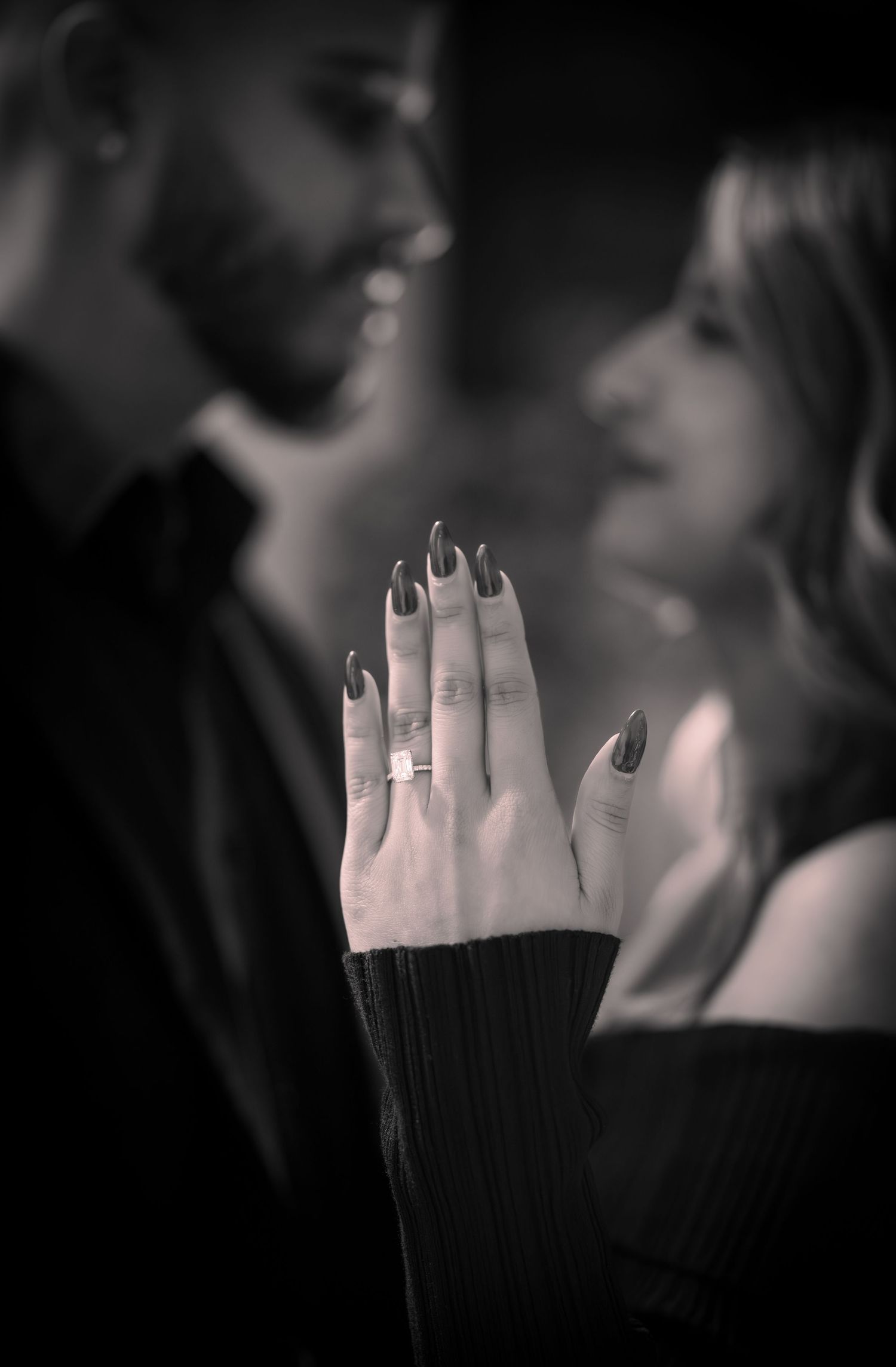 Close-up of engagement ring on hand with black sleeve detail.