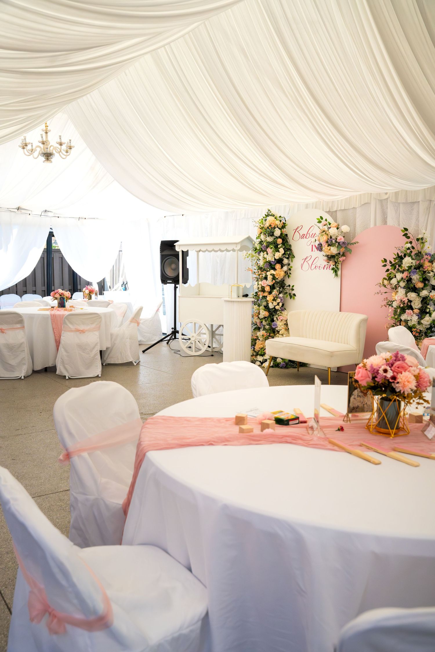 White draped wedding reception space with pink accents and elegant table settings.