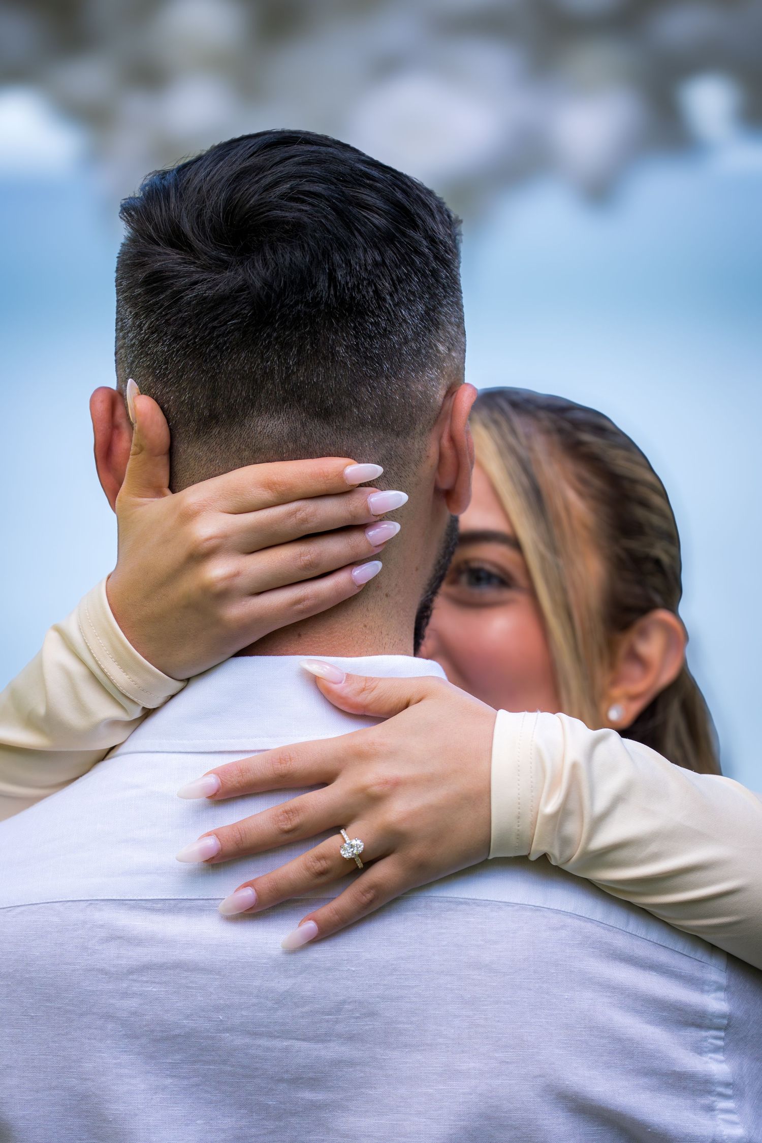 Close-up of intimate embrace showing hands and ring during romantic moment.