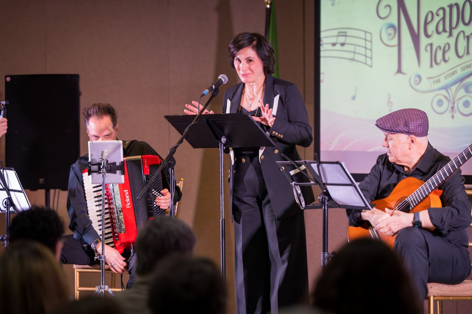 Singer performs at Neapolitan Ice Cream concert accompanied by accordion and classical guitar players.