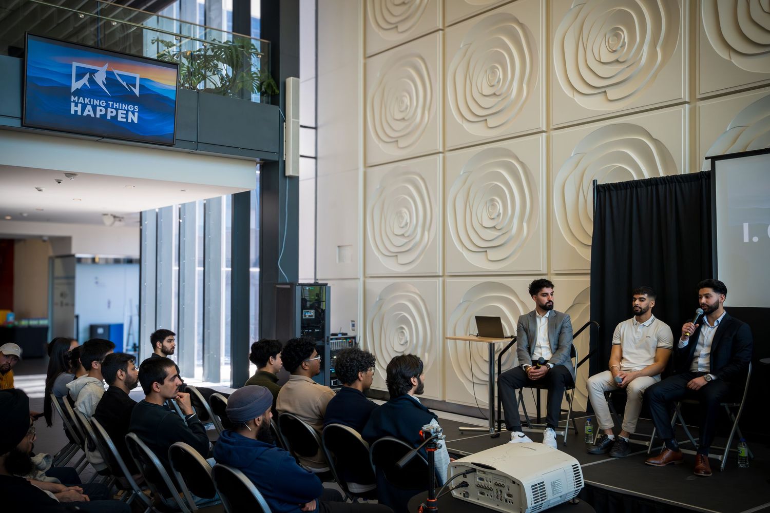 Modern conference venue with textured wall panels and audience seating.