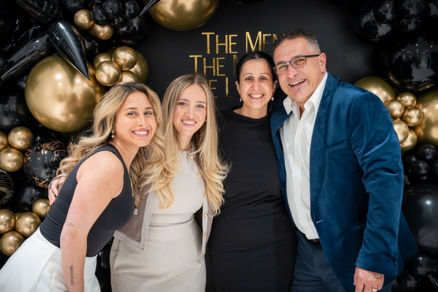 Social gathering with guests taking photos in front of luxurious balloon wall backdrop.