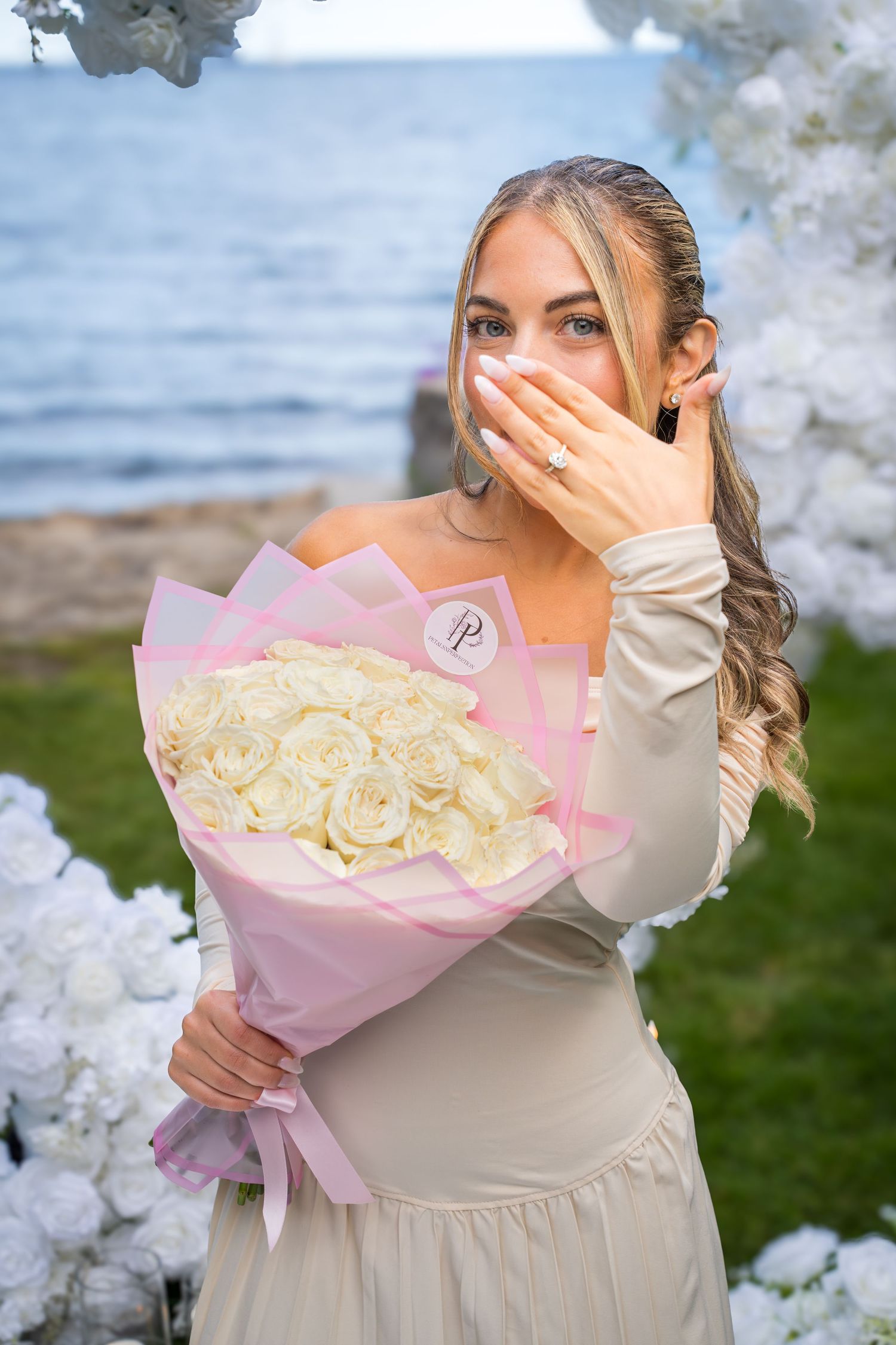 A surprised reaction captured during a romantic proposal with a bouquet of white roses.