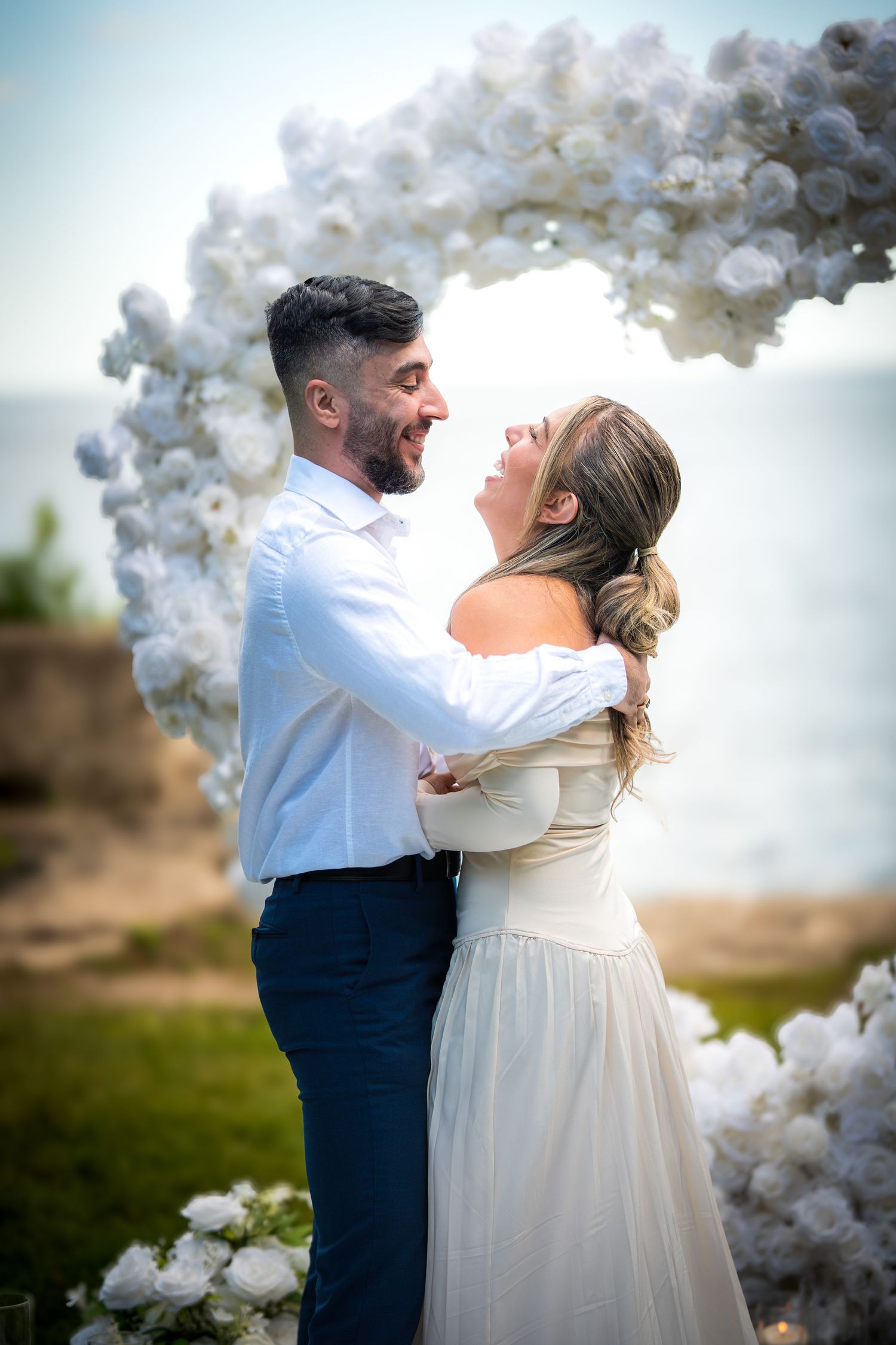 Couple sharing intimate moment under white balloon arch at outdoor ceremony.