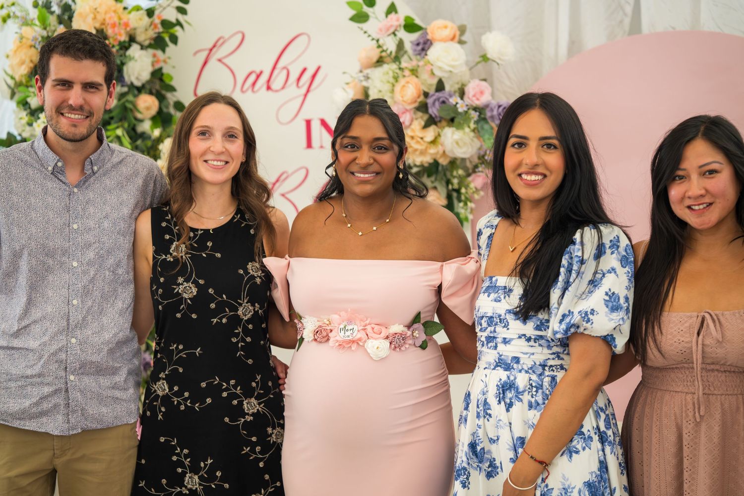 Group photo of baby shower guests posing in front of a floral backdrop.