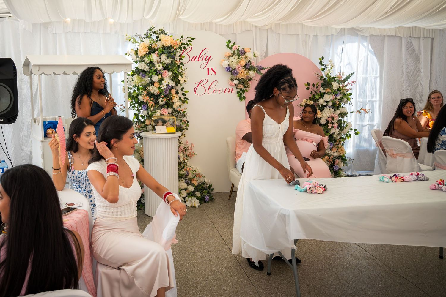 Wedding reception tent decorated with floral arrangements and white draping.