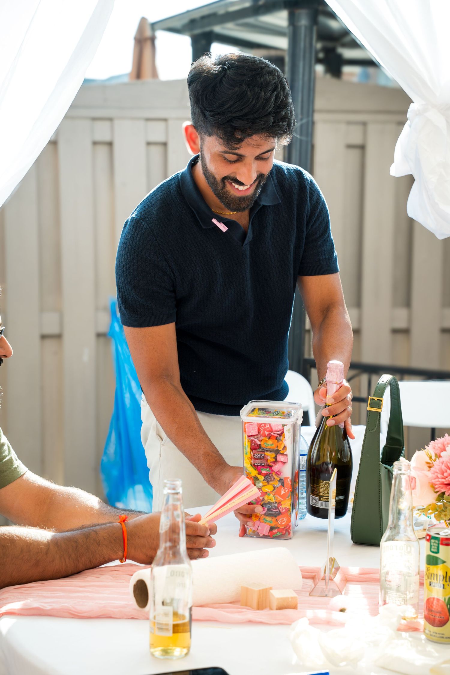 People enjoying drinks and snacks at a party table with white tablecloth.