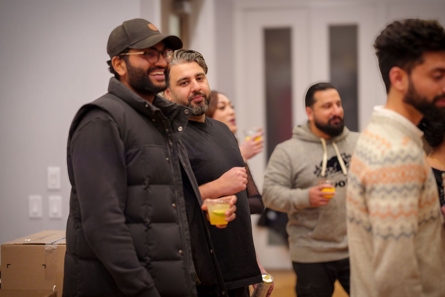 Group enjoying beverages and conversation at indoor holiday gathering.