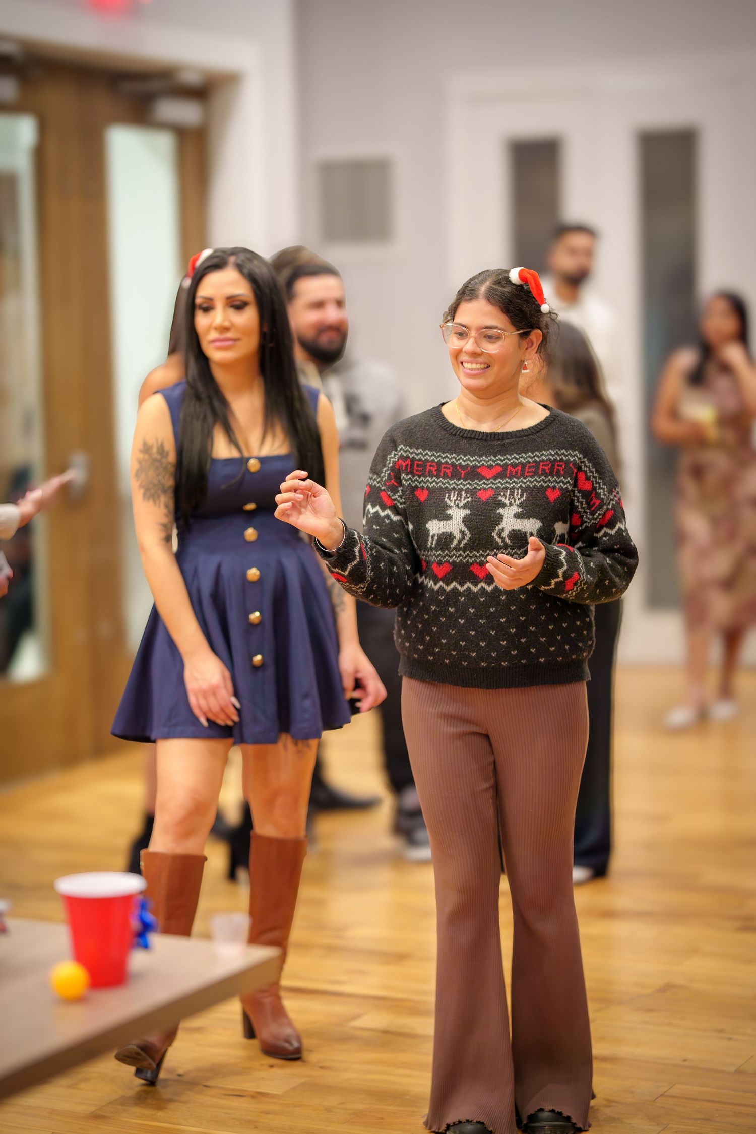 People dancing and socializing at an indoor party with hardwood floors and festive atmosphere.