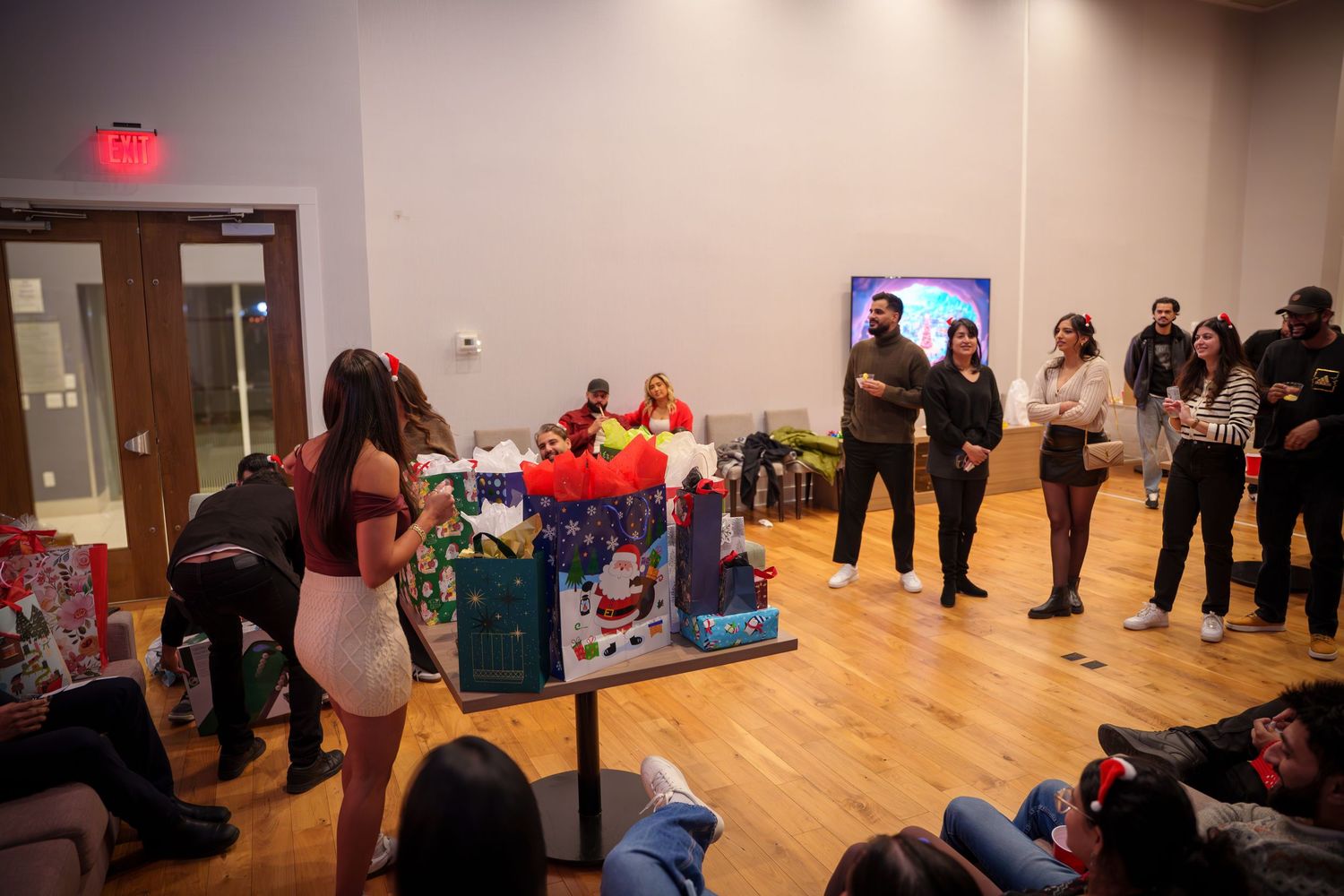 Wide view of party room with people gathered around game setup on wooden floor.