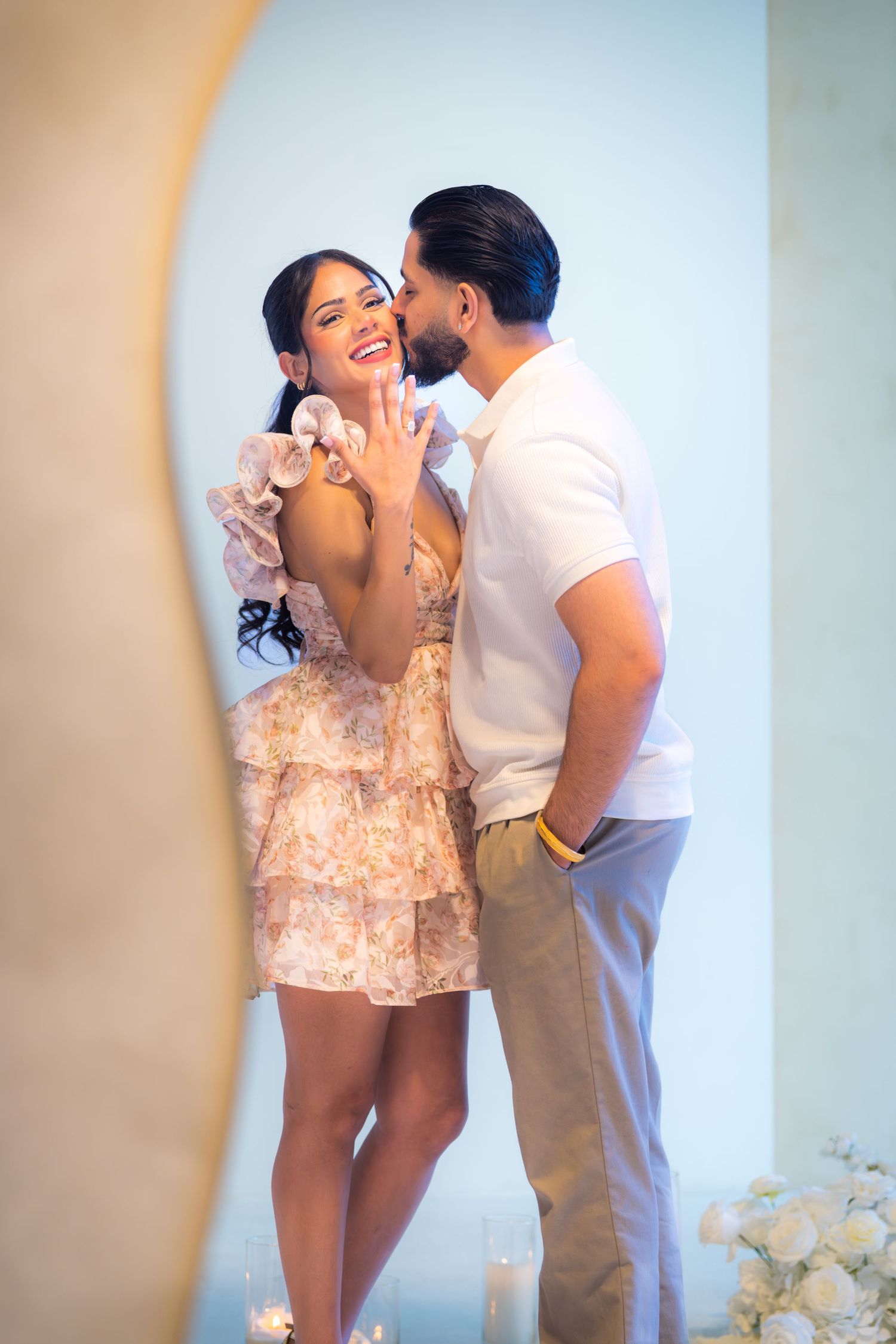 Joyful woman displaying engagement ring while man whispers to her during romantic proposal celebration.