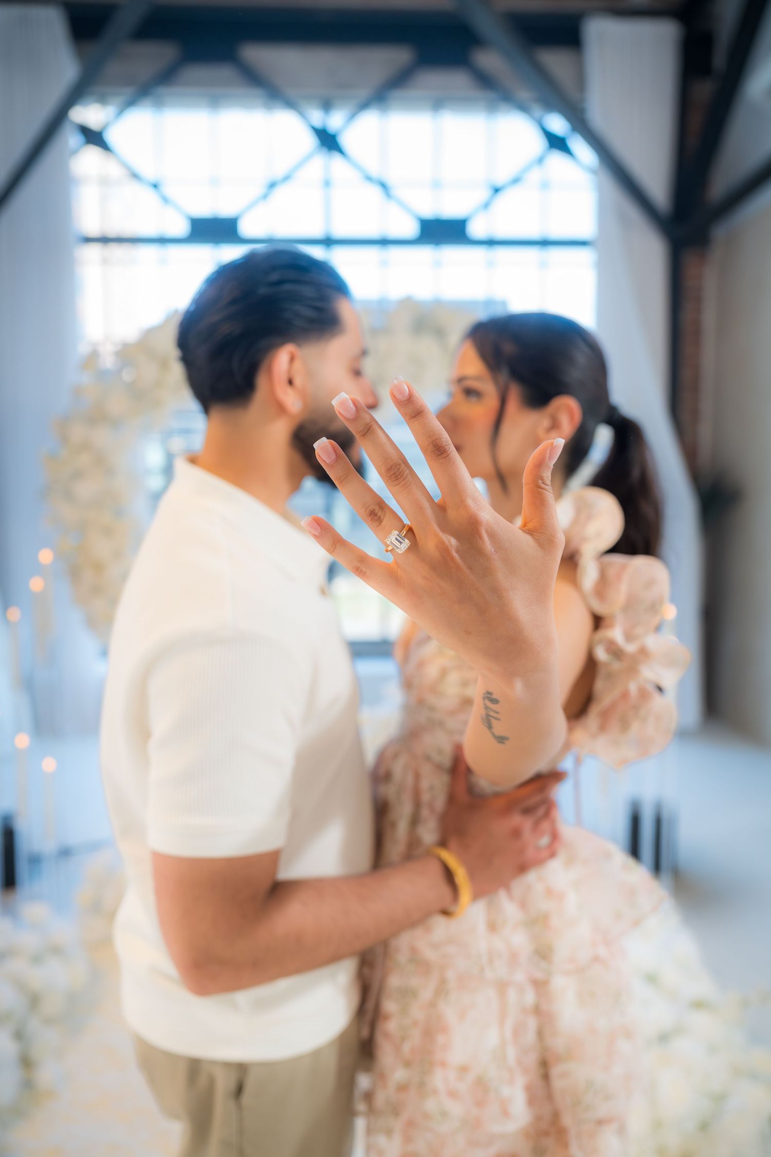 A newly engaged woman shows off her diamond ring while kissing her fiance at a proposal setup.