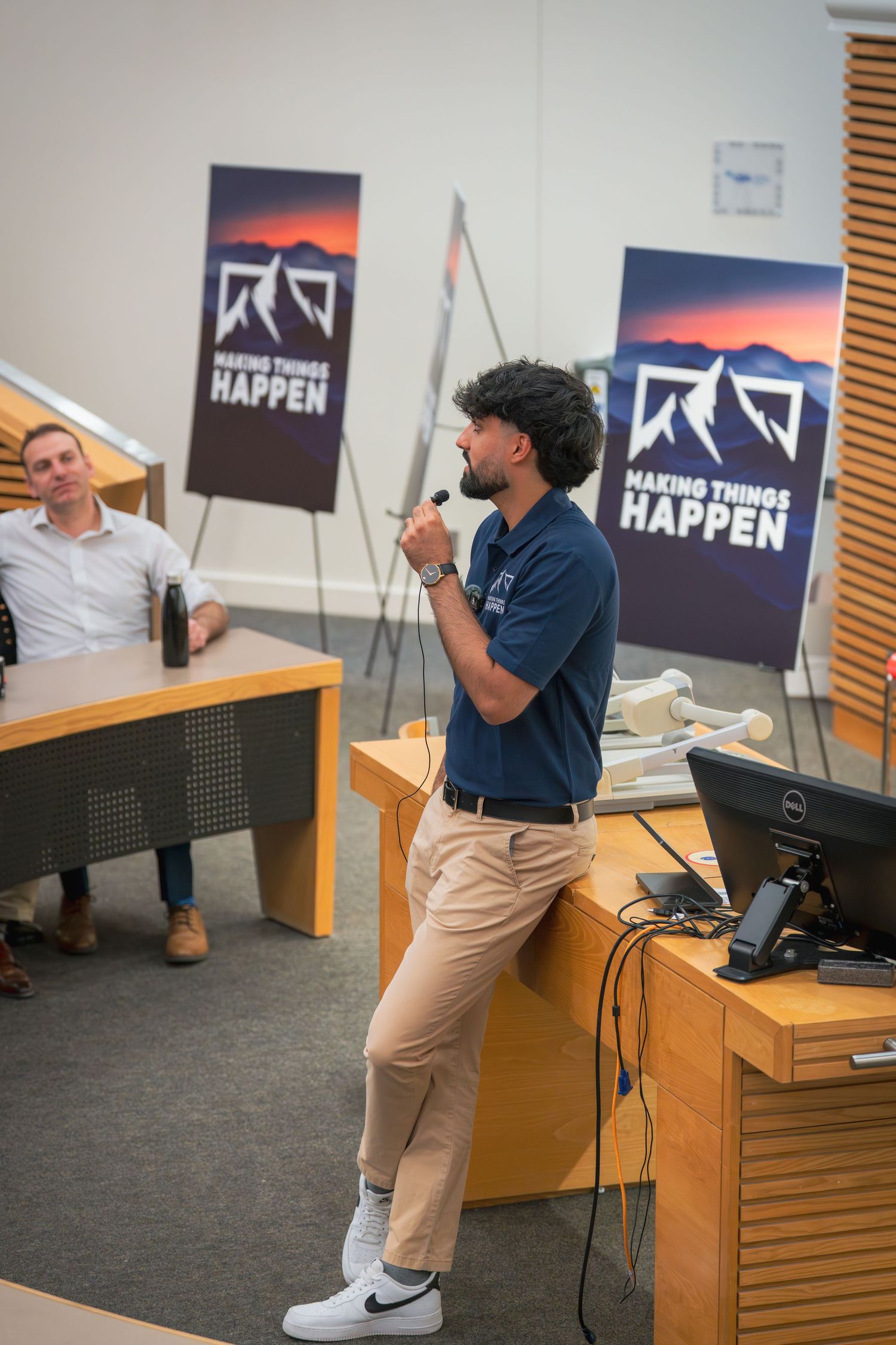 Presenter giving a talk in business casual attire with motivational banners in the background.