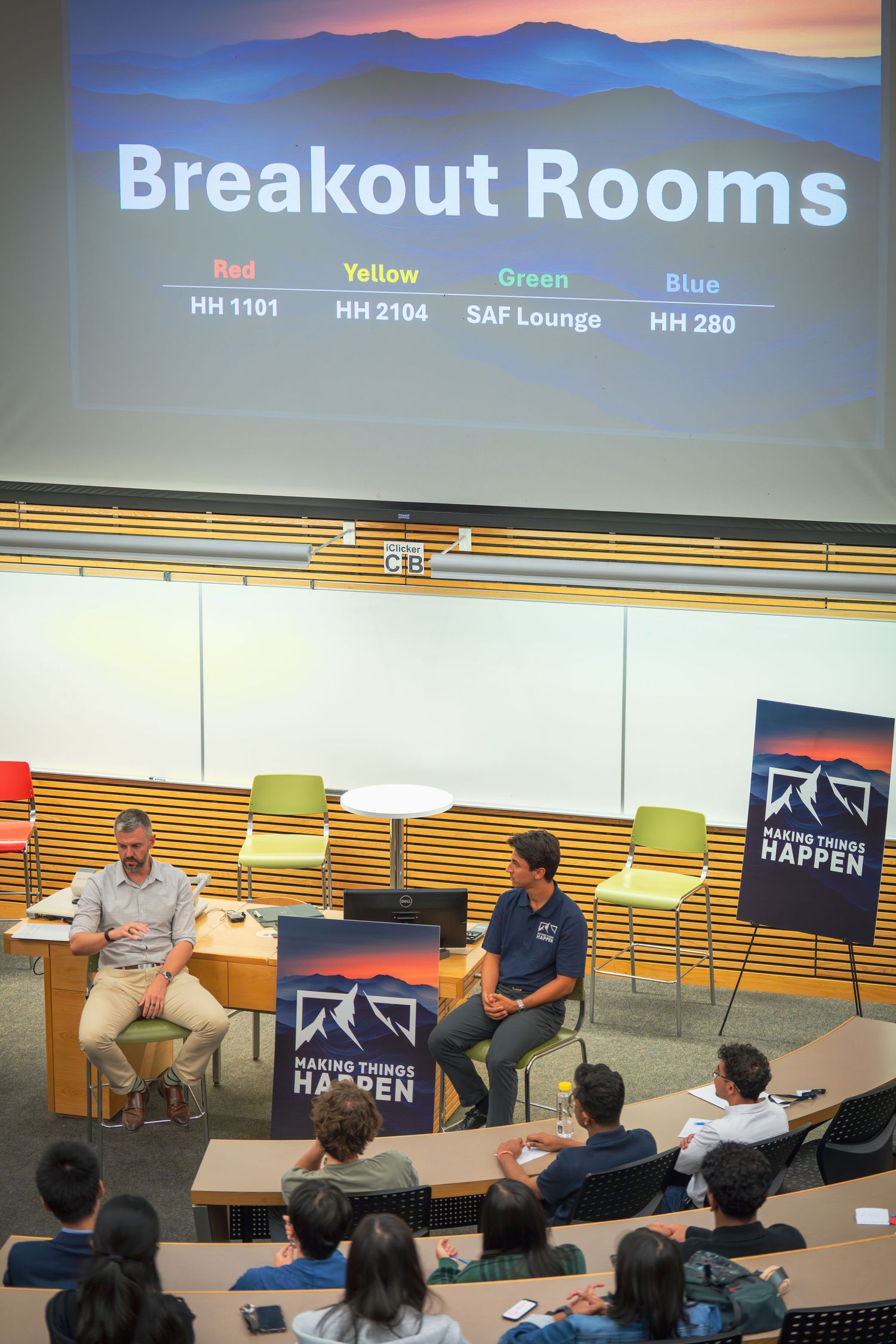 Breakout rooms schedule displayed on projection screen during educational event.
