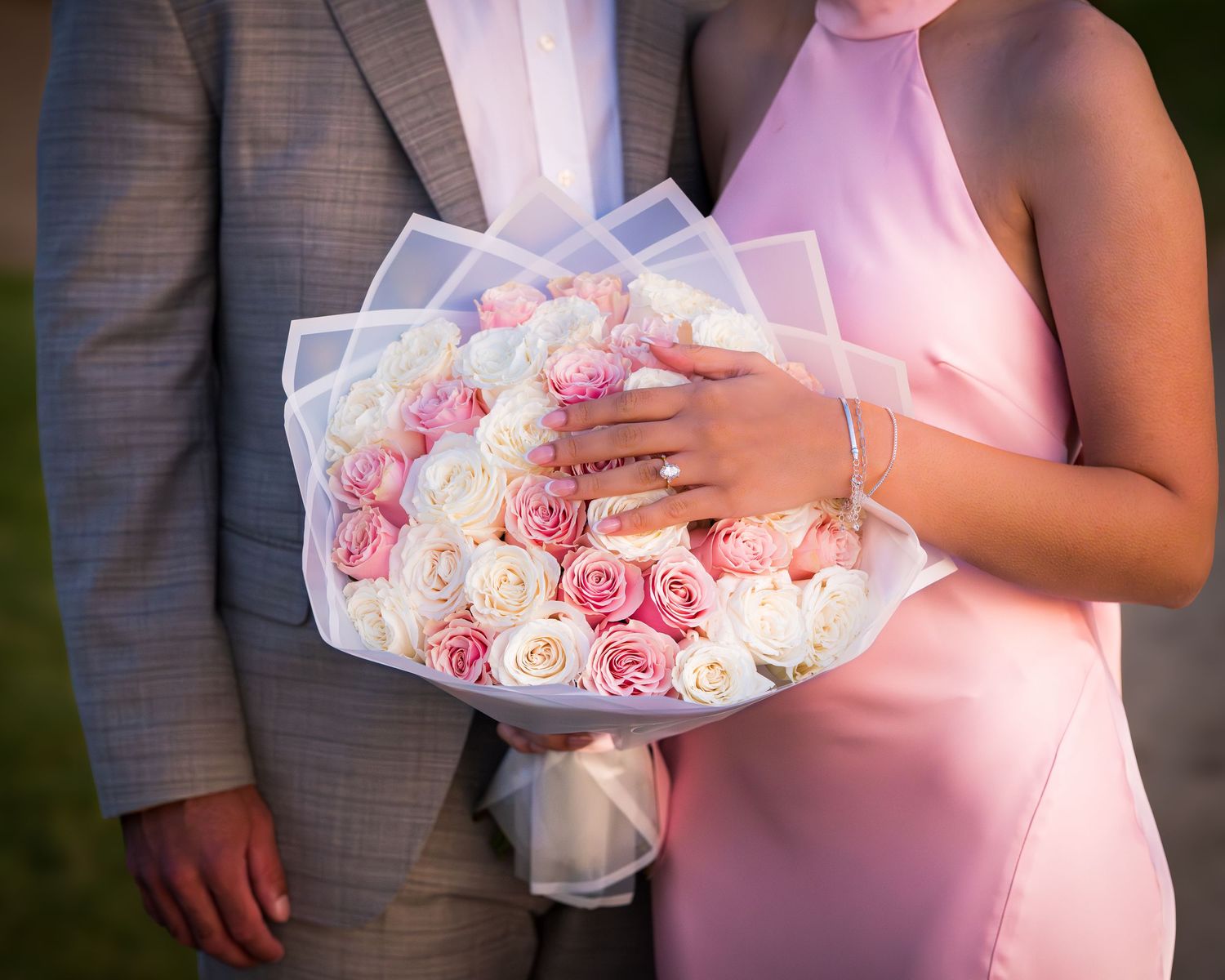 A couple poses with a beautiful bouquet of pink and white roses during an outdoor photoshoot.