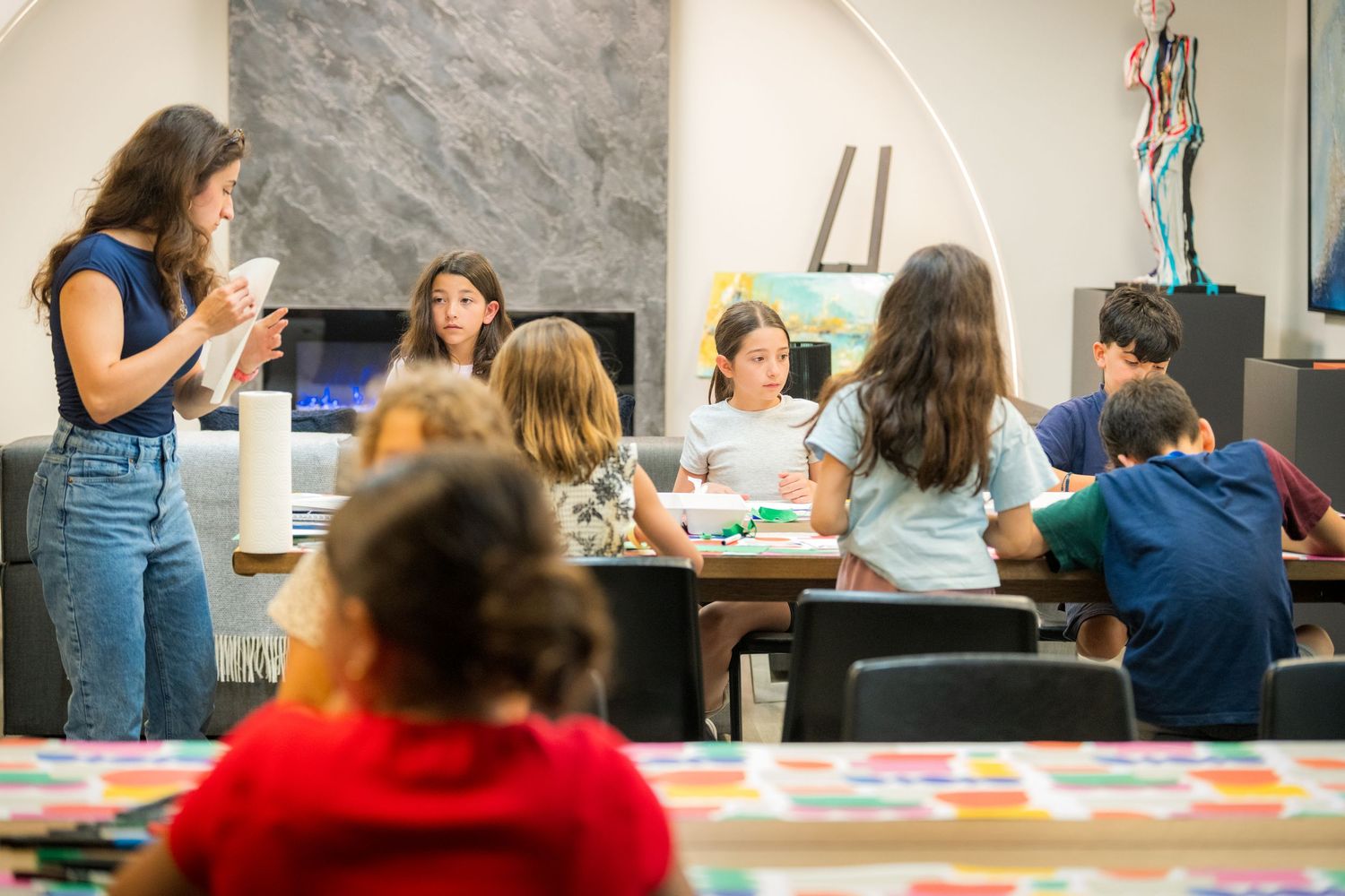 Children participate in a group art workshop session in a bright modern gallery space.