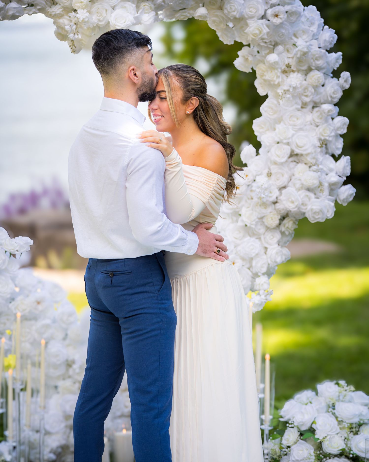 Wedding ceremony site with elegant white floral arch and romantic couple.