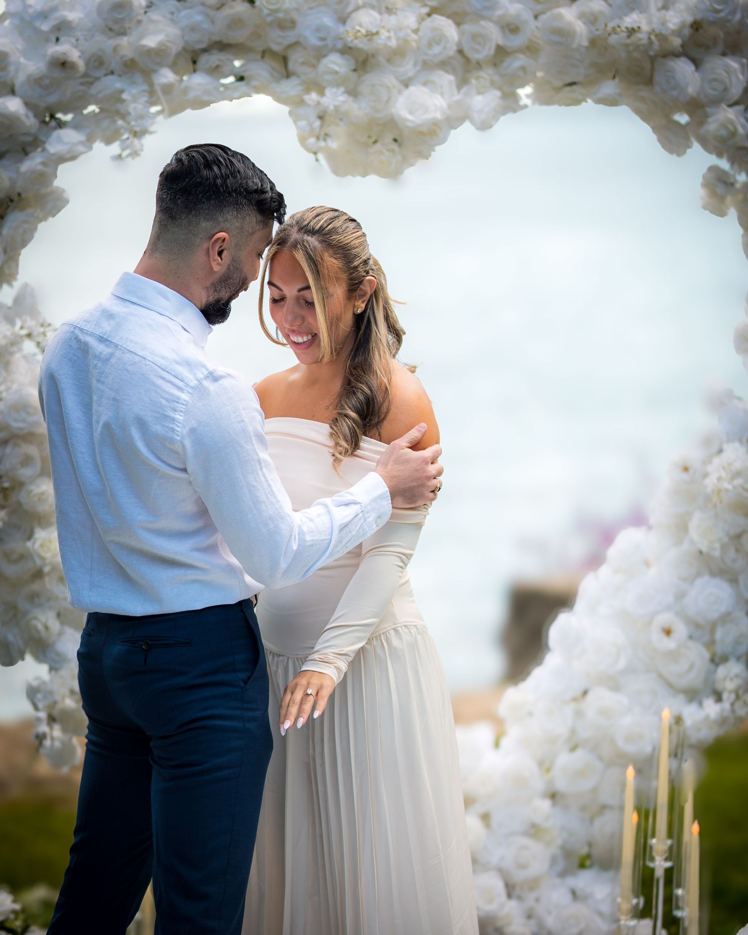 Intimate wedding moment captured under decorative white balloon arch.