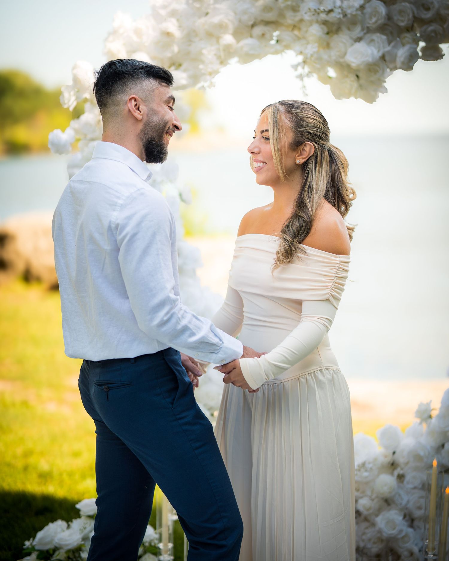 Romantic couple dancing together under white floral decorations at sunset.