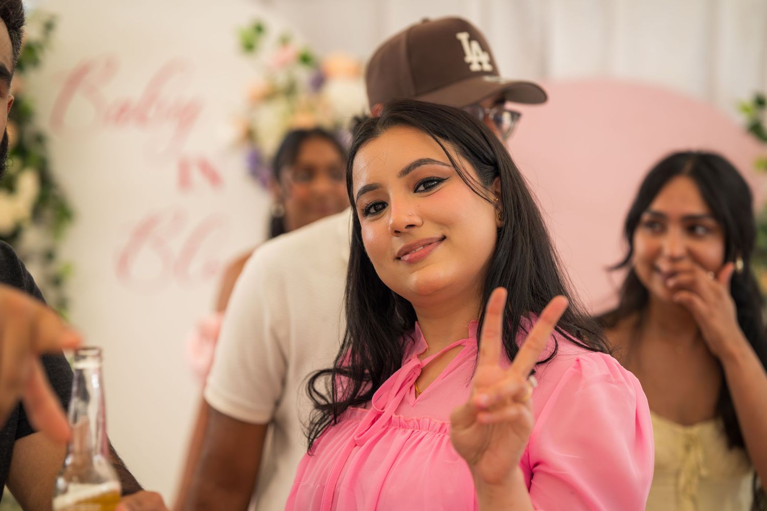 Guests smile and celebrate during a pink-themed baby shower party.
