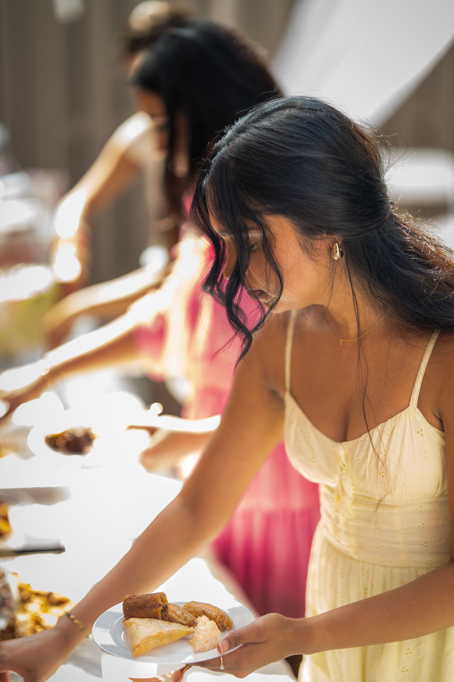 A person in a yellow dress reaching for food at a buffet table.