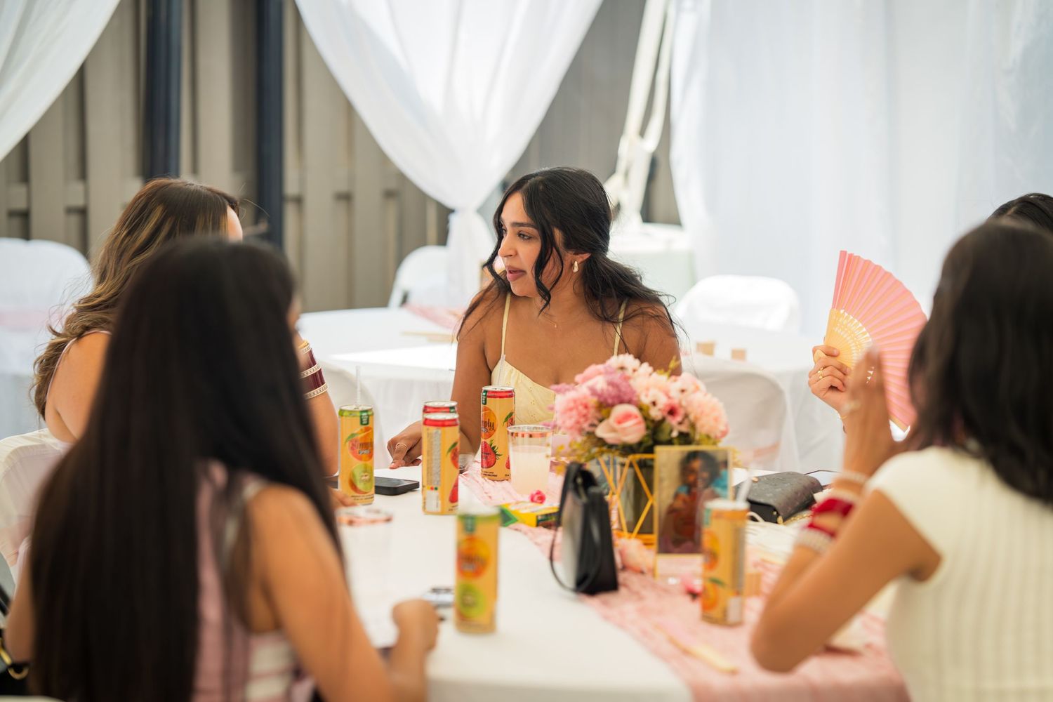 Guests seated at long tables with pink decorations and white draping.