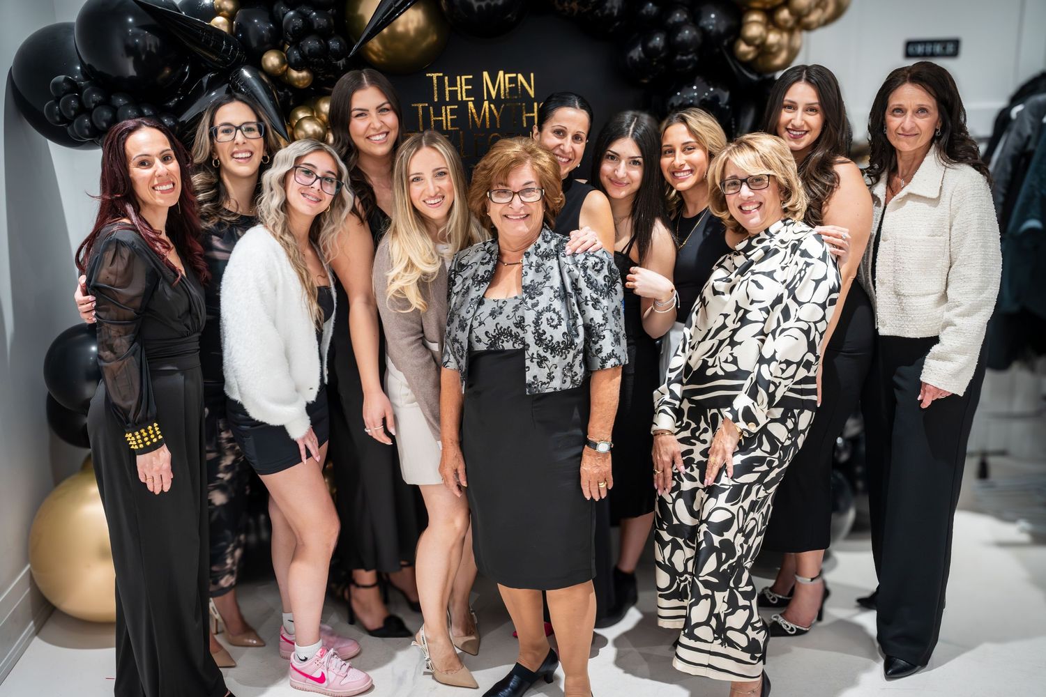 Large group photo of event attendees in front of decorative balloon wall.