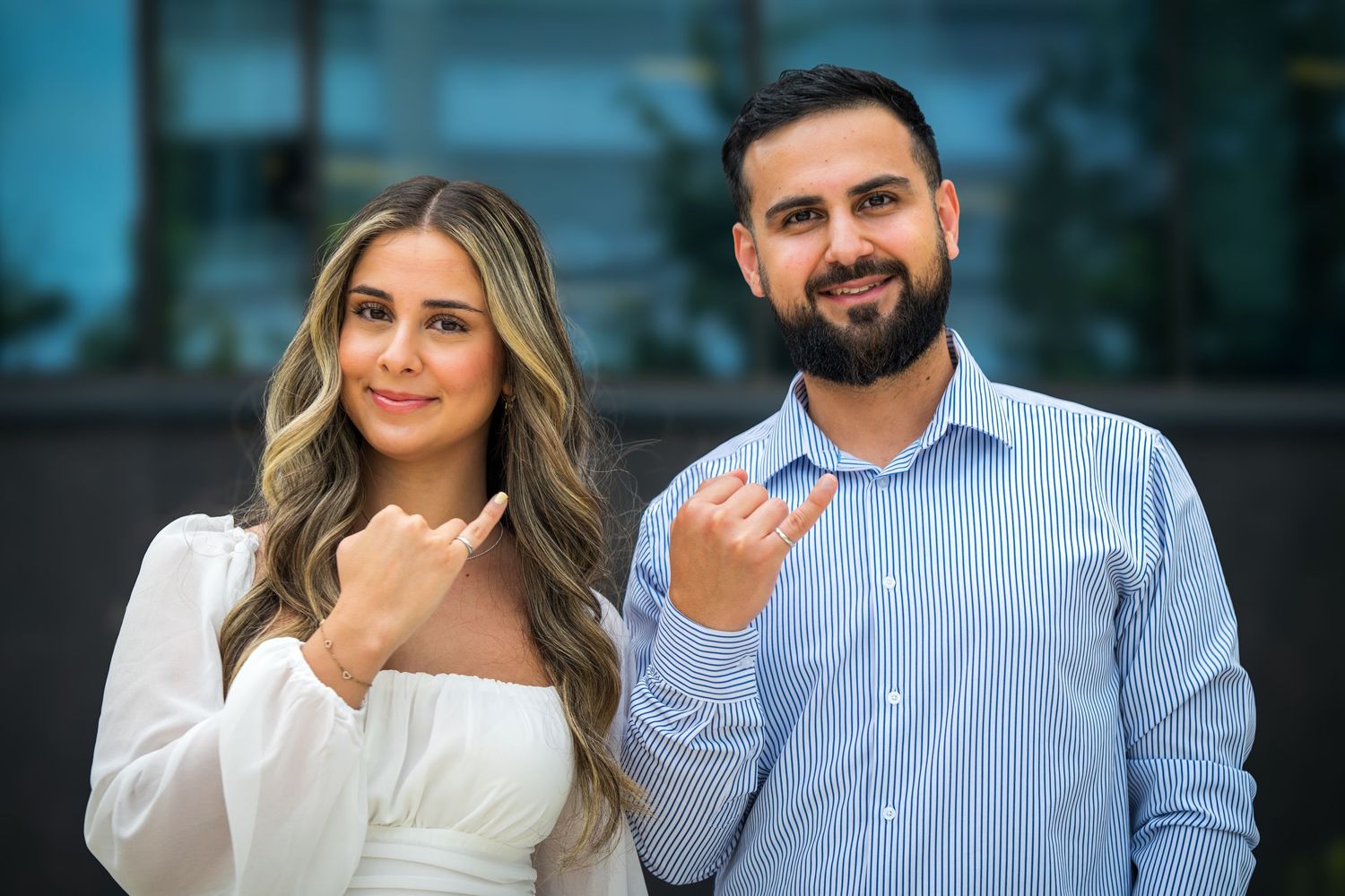 A couple poses together outdoors wearing coordinating white and blue outfits.