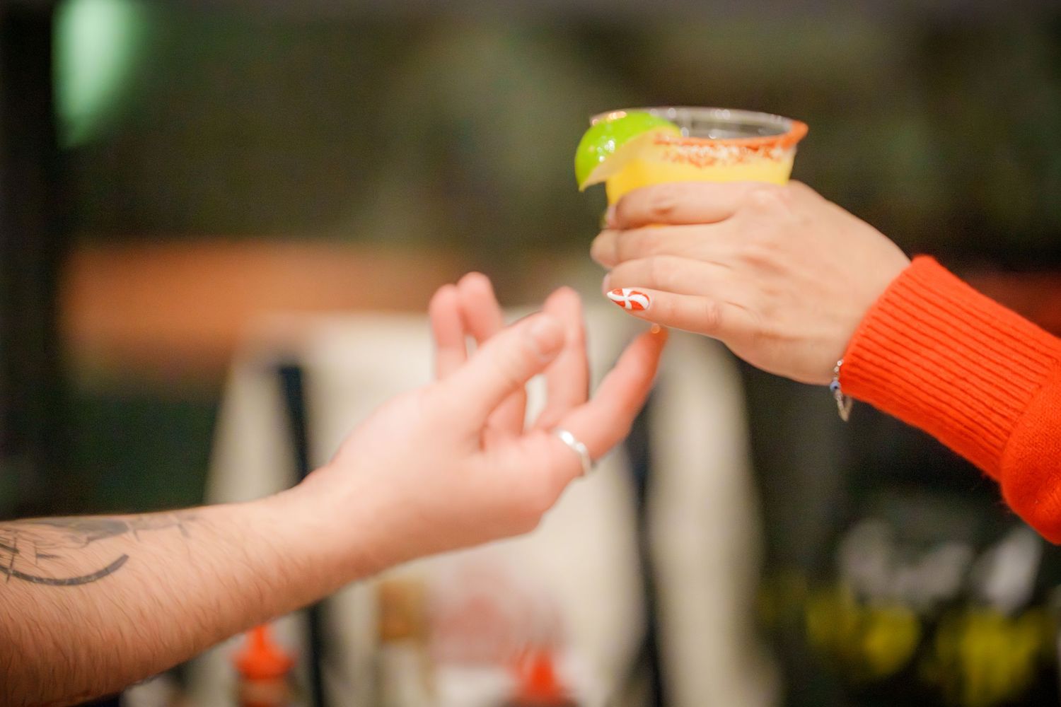 Close-up shot of hands passing objects across a table during a gathering.