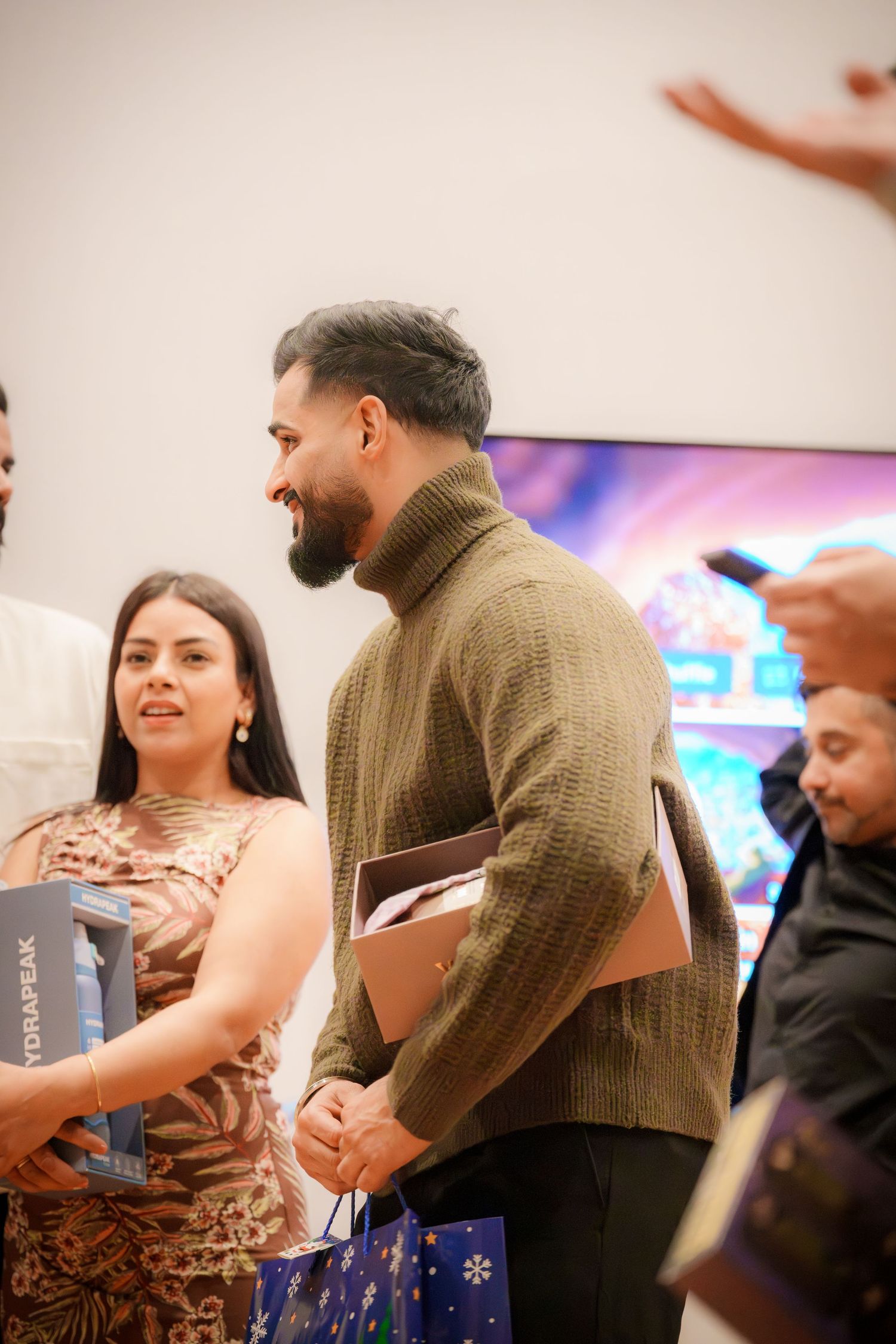 People exchanging gifts or items at an indoor celebration event.