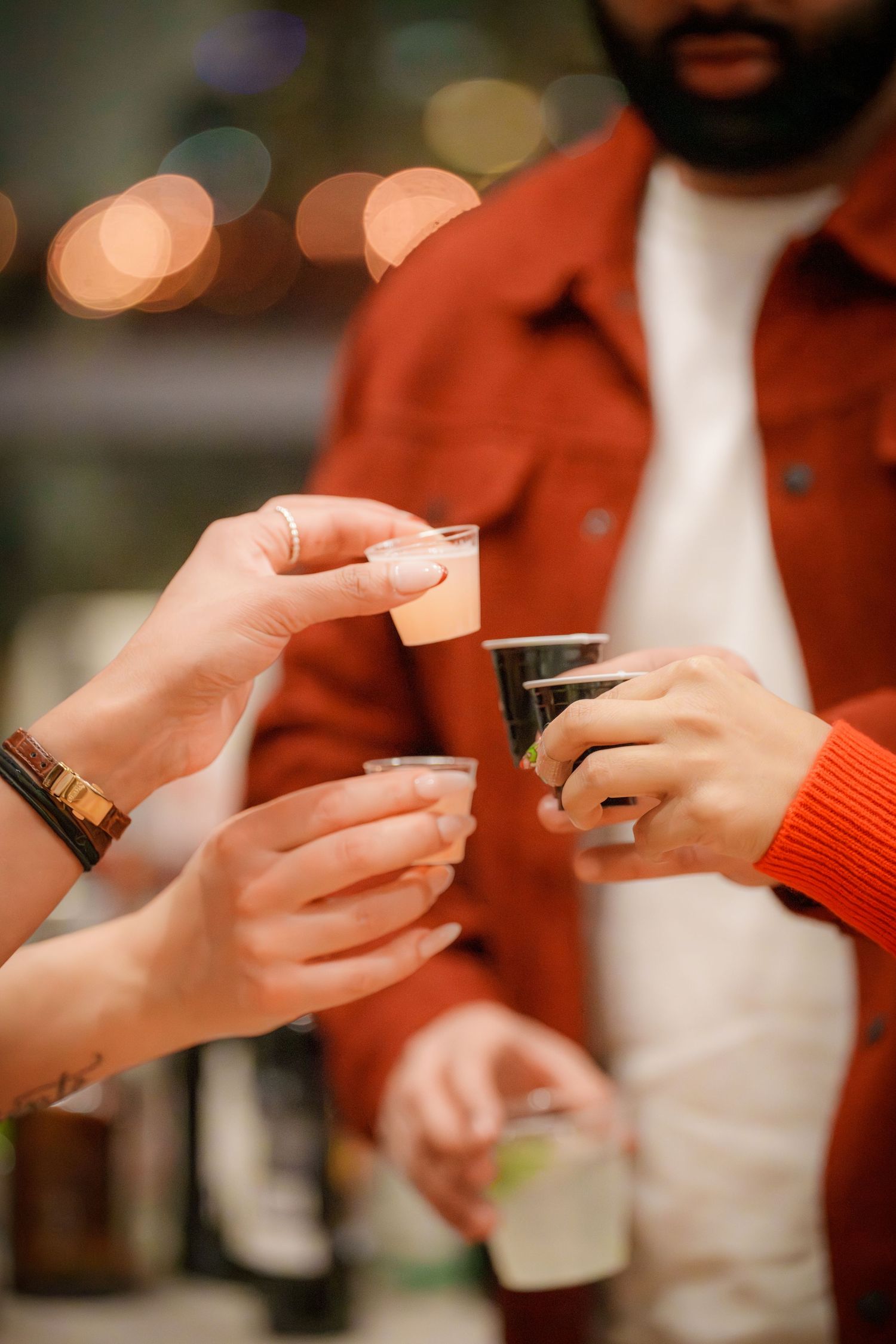 Close-up of hands passing drinks at a social gathering.