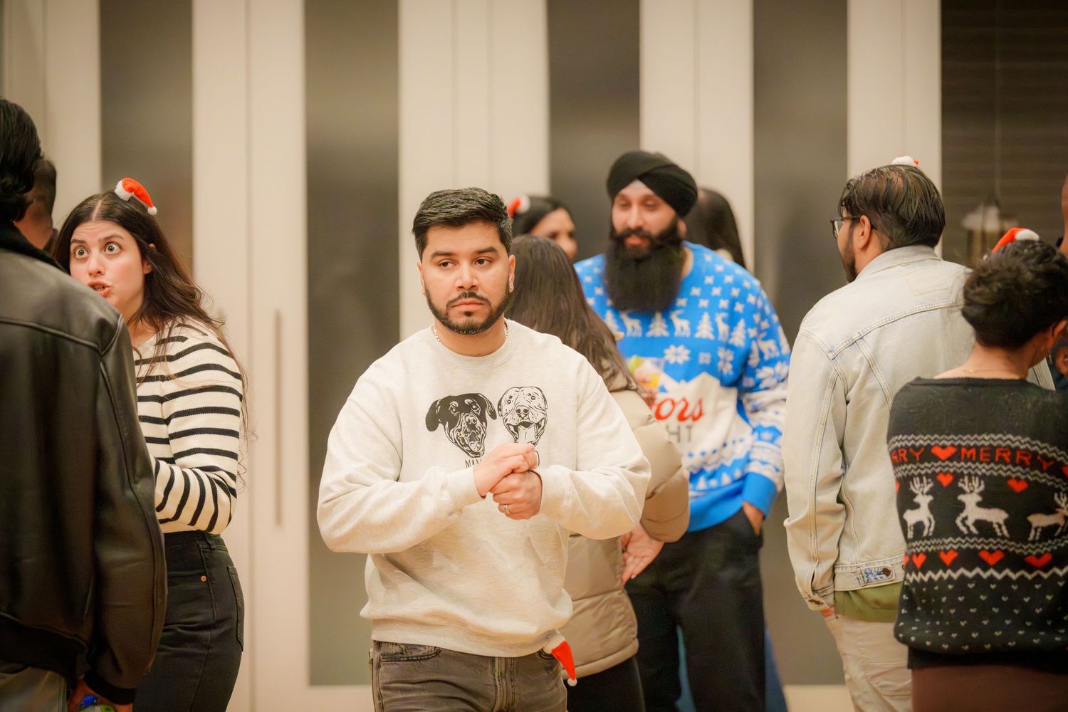 People mingling and socializing at an indoor event with striped wall background.