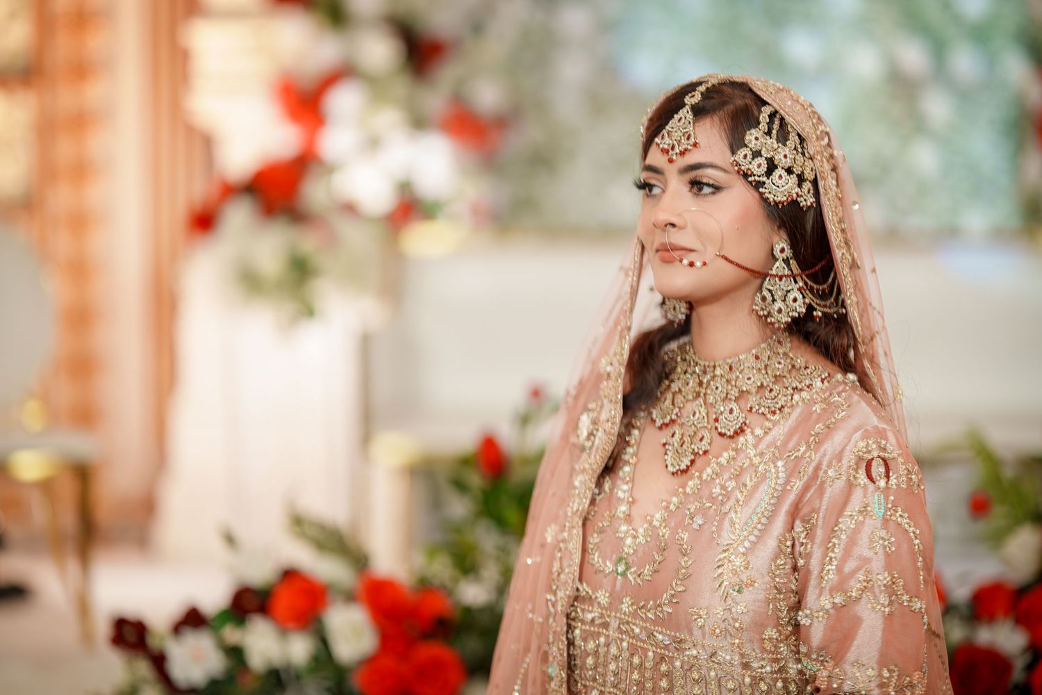 Bridal portraits featuring intricate peach lehenga with detailed embellishments and red floral decor.