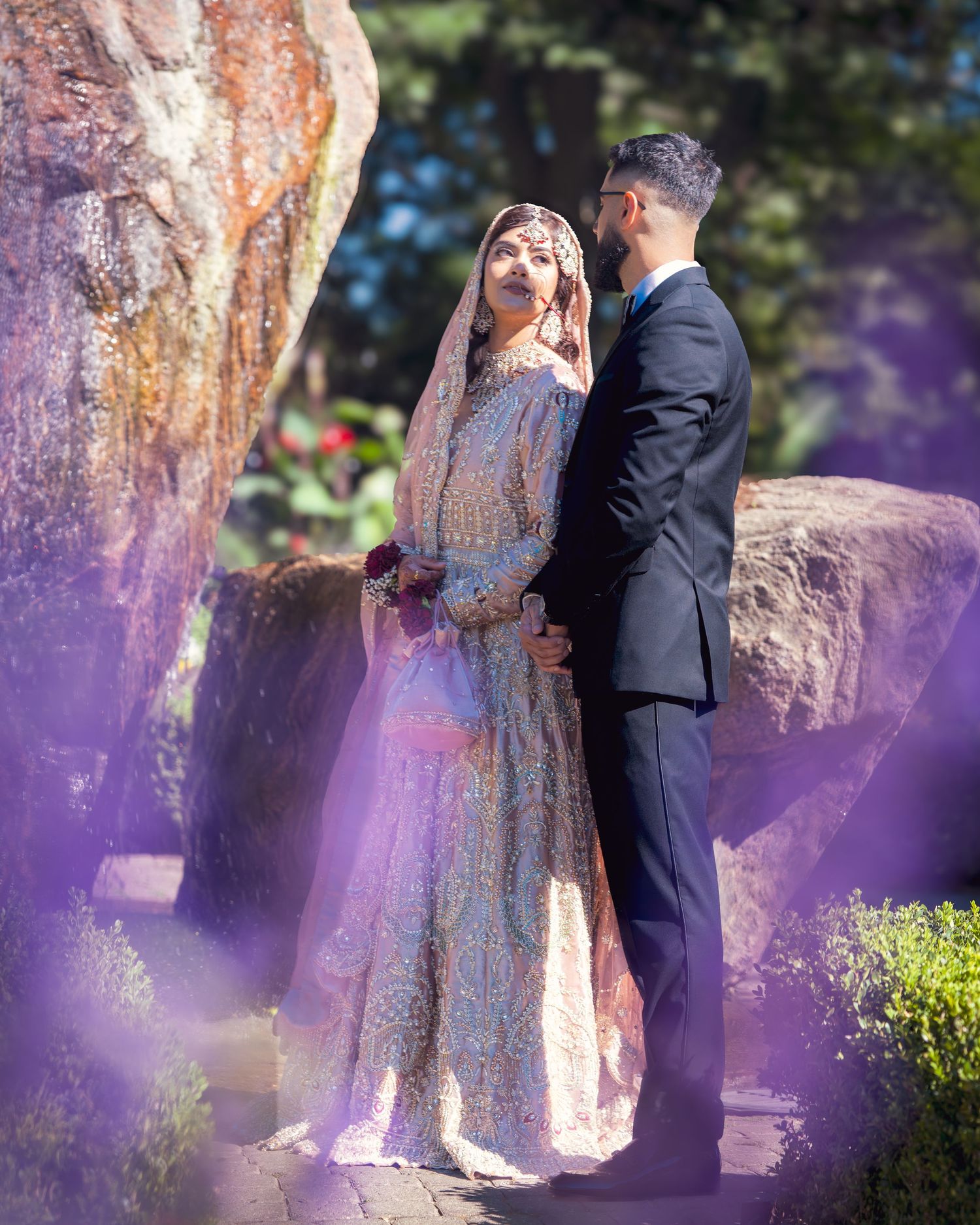 Artistic wedding photos with purple light effects and natural garden elements creating romantic atmosphere.