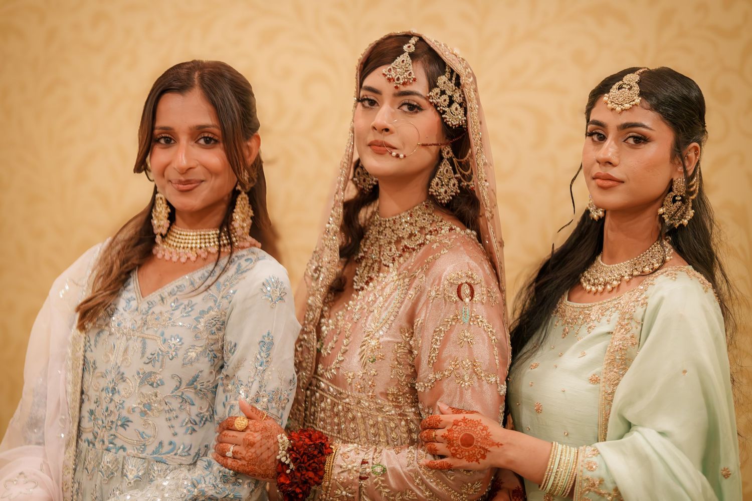 Wedding party group photos in pastel traditional outfits against warm backdrop.