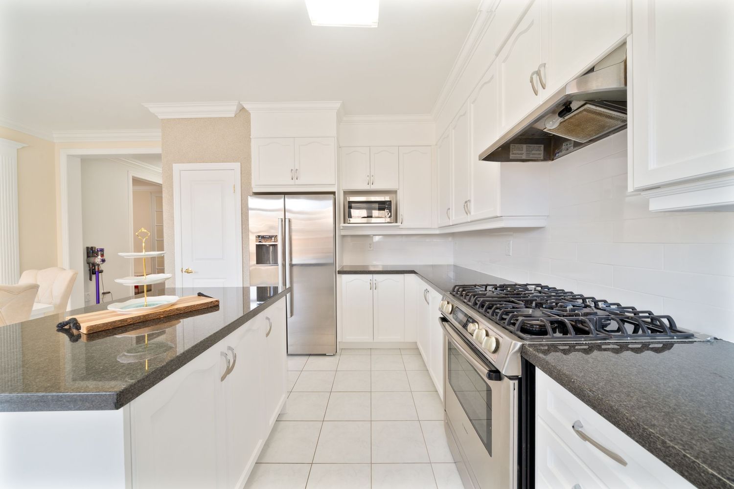 Modern white kitchen with sleek cabinets, black countertops, and stainless steel appliances in a bright open layout.