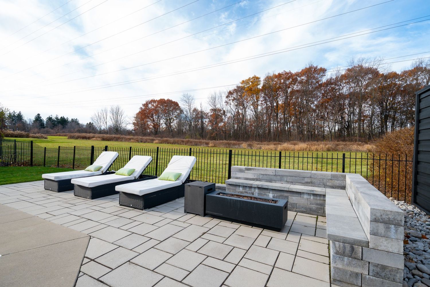 Luxurious outdoor patio furniture with gray cushions and loungers arranged on stone tiles overlooking a scenic landscape.