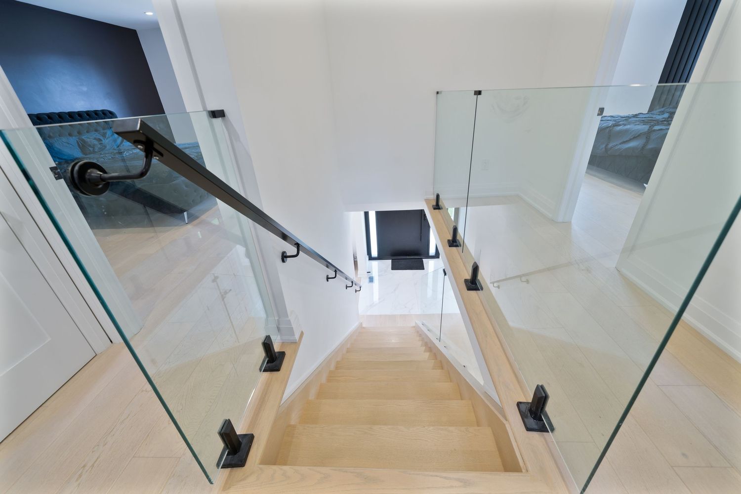 Modern glass staircase with wooden treads and sleek metal handrails in a bright contemporary interior space.