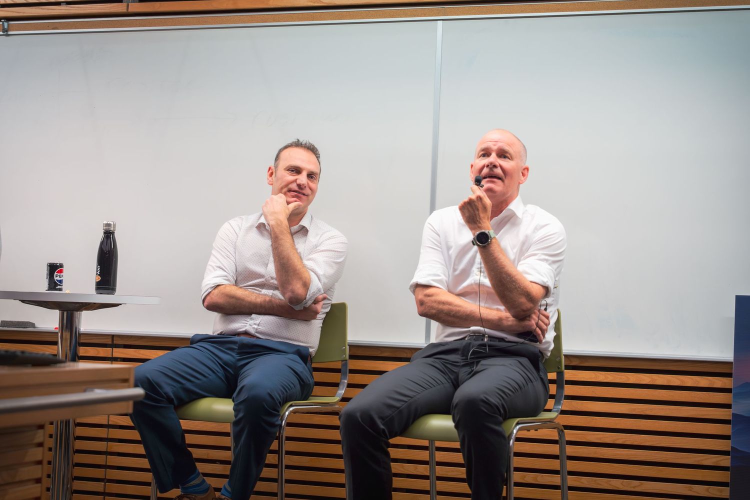 Participants engaged in discussion while seated in chairs against a wood-paneled wall.